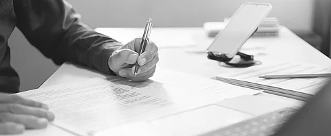 Hand eines Geschäftsmannes prüft Dokument im Büro